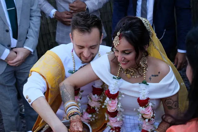 Krishna and Matt playing the ring game in their wedding outfits, surrounded by guests